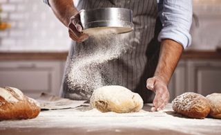 Man sifting flour on the bread dough